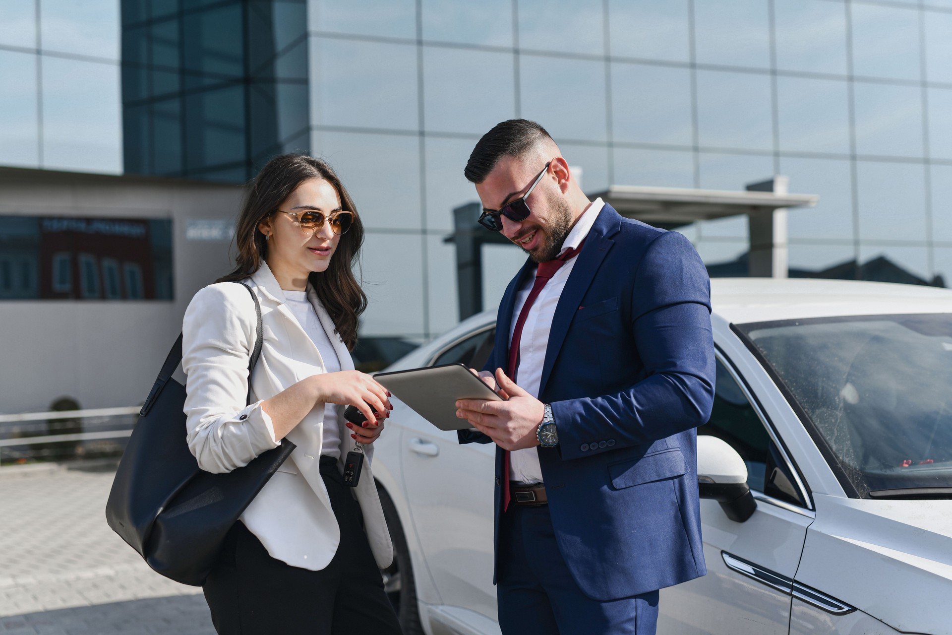 Handsome Male in Modern Suit Showing Emails to Female Colleague on Company's Parking Lot